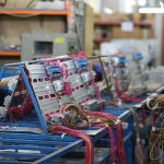 Technicians assembling electric motor components with colorful wiring on an industrial production line inside a manufacturing facility.