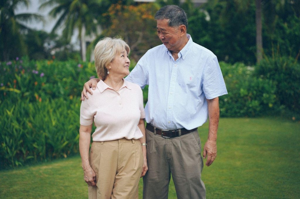 A happy older couple enjoying a stroll through a beautifully landscaped garden and walking path, highlighting the peaceful outdoor lifestyle at Carleton Place retirement residences.